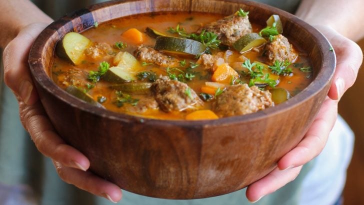 Woman holding a big wooden bowl of Mexican Meatball Soup