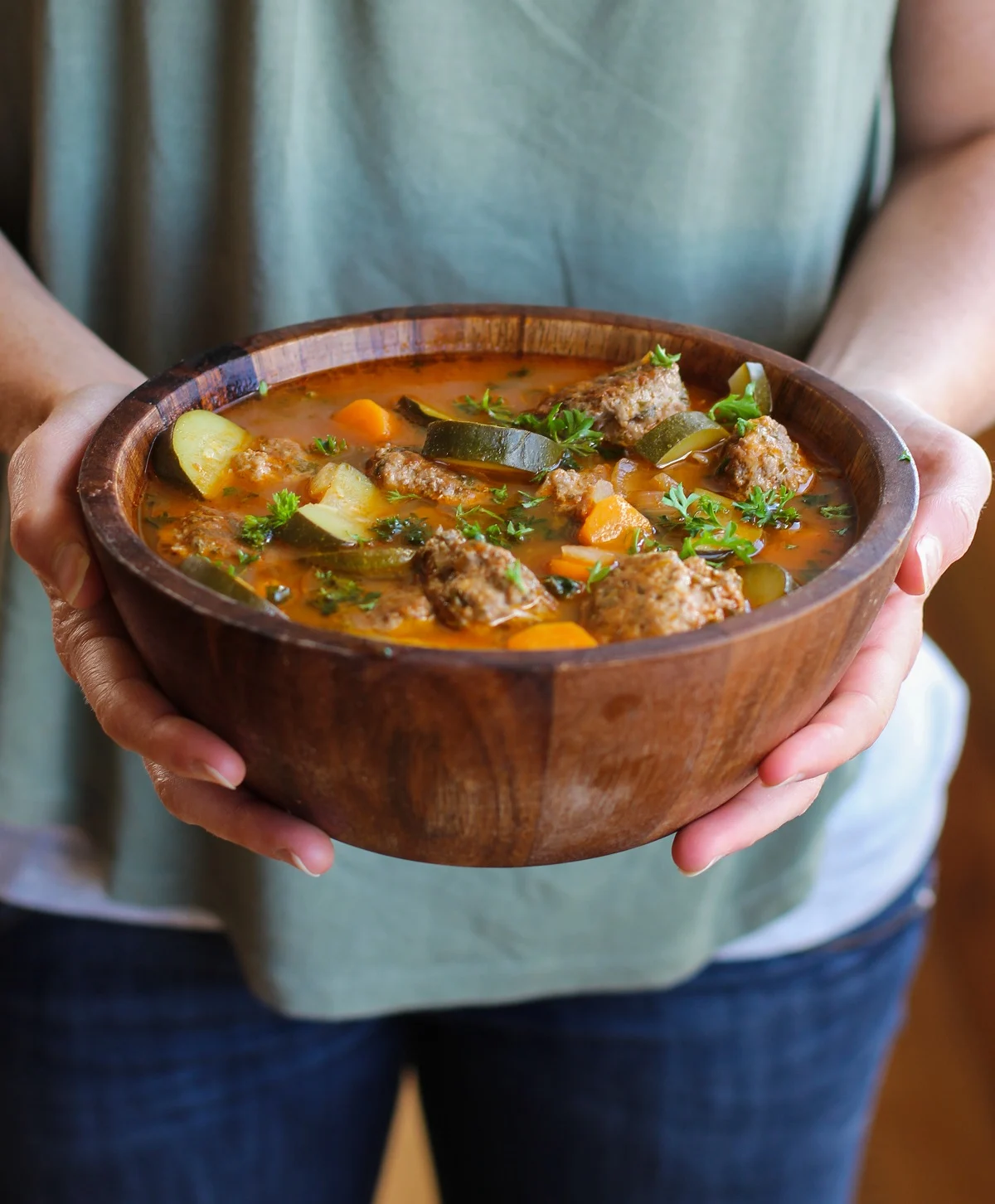Woman holding a big wooden bowl of Mexican Meatball Soup