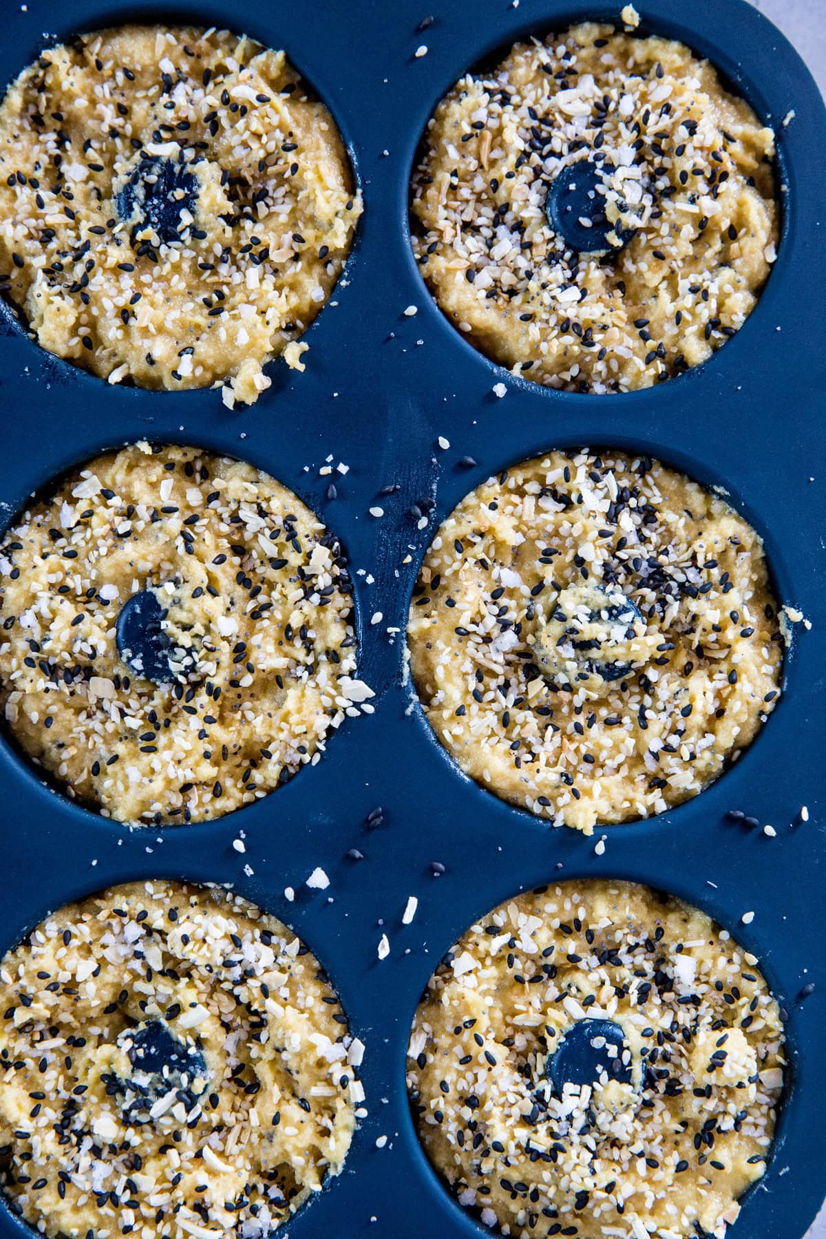 Silicon bagel mold full of bagel batter, sprinkled with everything seasoning.