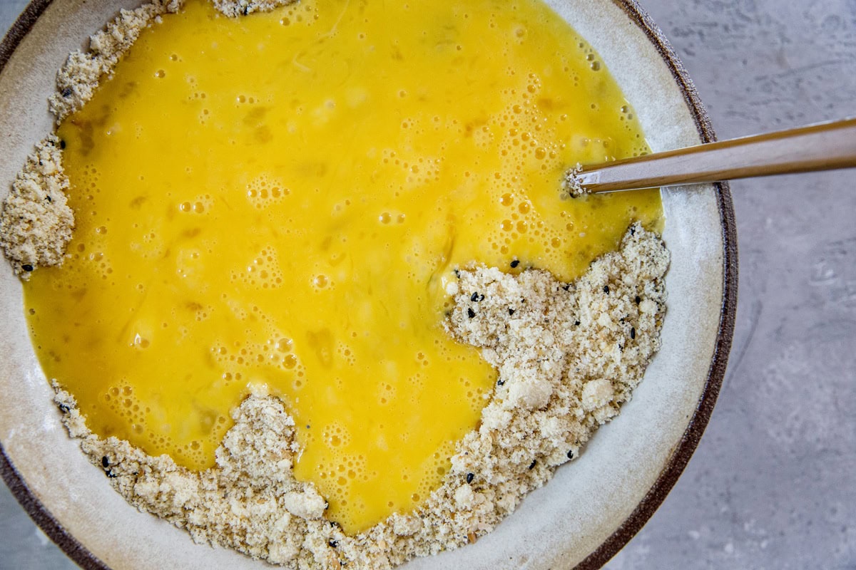 Mixing bowl full of wet ingredients with dry ingredients poured on top, ready to be mixed in.