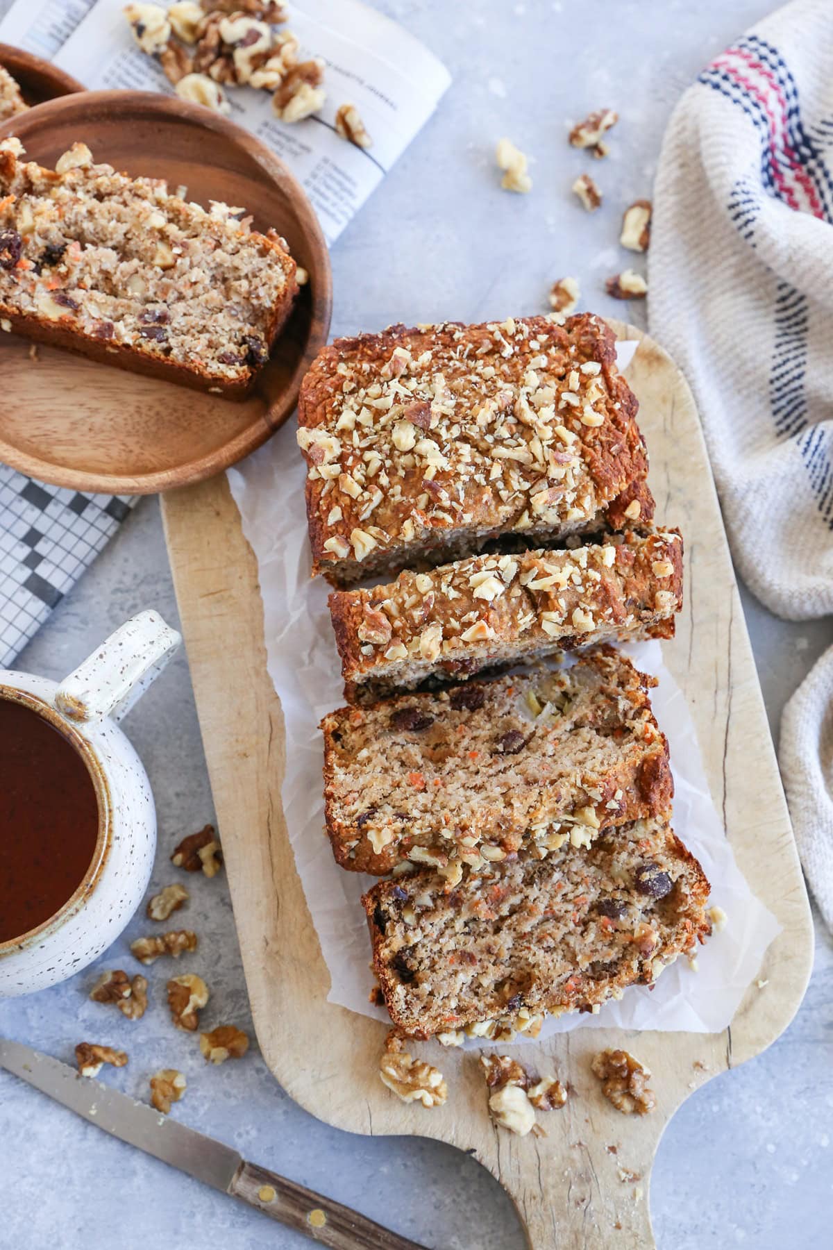 Wooden cutting board with a loaf of carrot cake banana bread cut into slices on top.