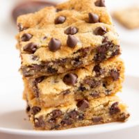 Three cookie bars stacked on top of each other on a white plate.