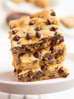 Three cookie bars stacked on top of each other on a white plate.