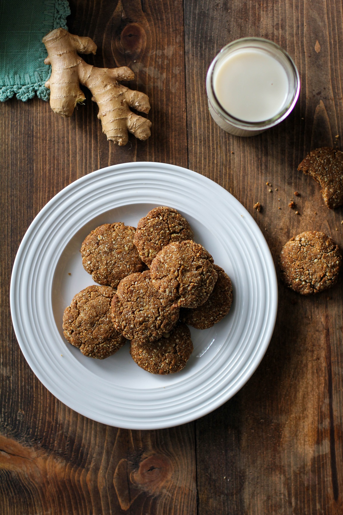 Paleo Gingerbread Cookies on a white plate with a teal napkin and a glass of almond milk to the side