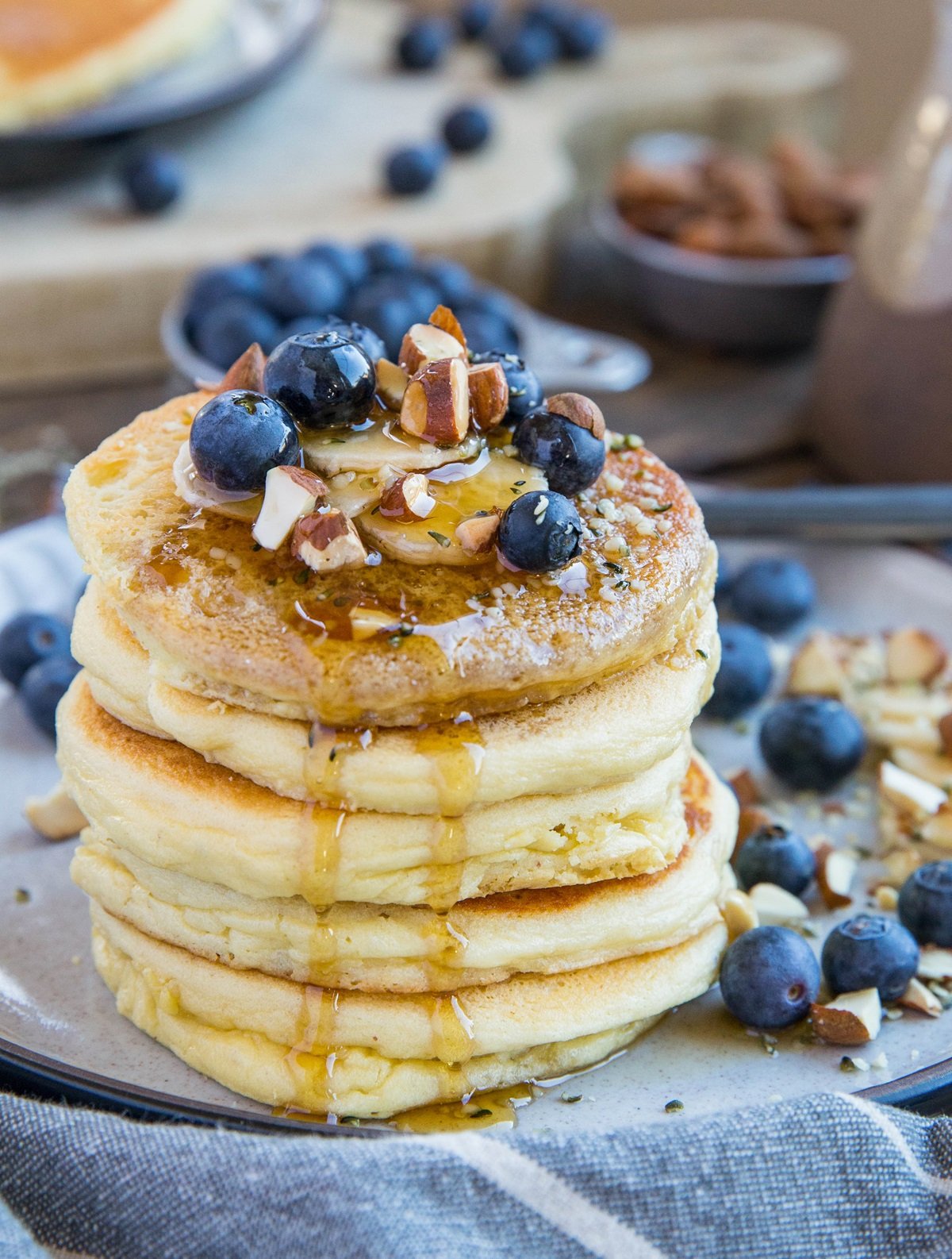 Stack of paleo almond flour pancakes with fresh fruit on top and syrup dripping down.