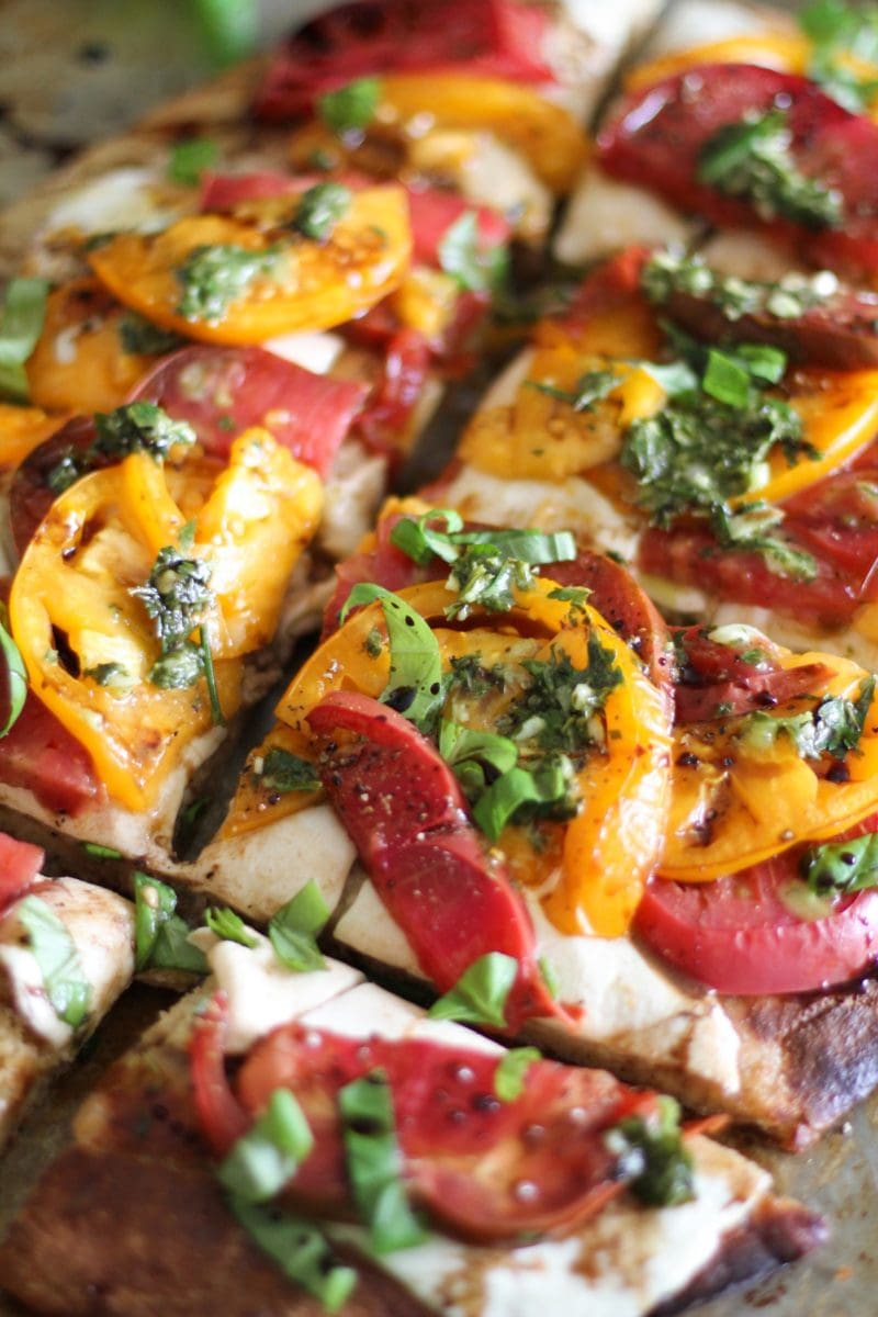 Caprese Pizza Recipe on top of almond flour pizza crust with chimichurri sauce drizzled on top.
