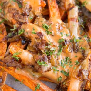 Sweet Potato Animal Style Fries - loaded fries with cheese, caramelized onions and special sauce on a parchment-lined baking sheet.