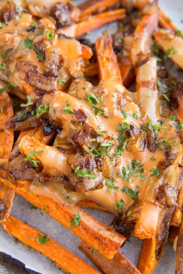 Sweet Potato Animal Style Fries - loaded fries with cheese, caramelized onions and special sauce on a parchment-lined baking sheet.