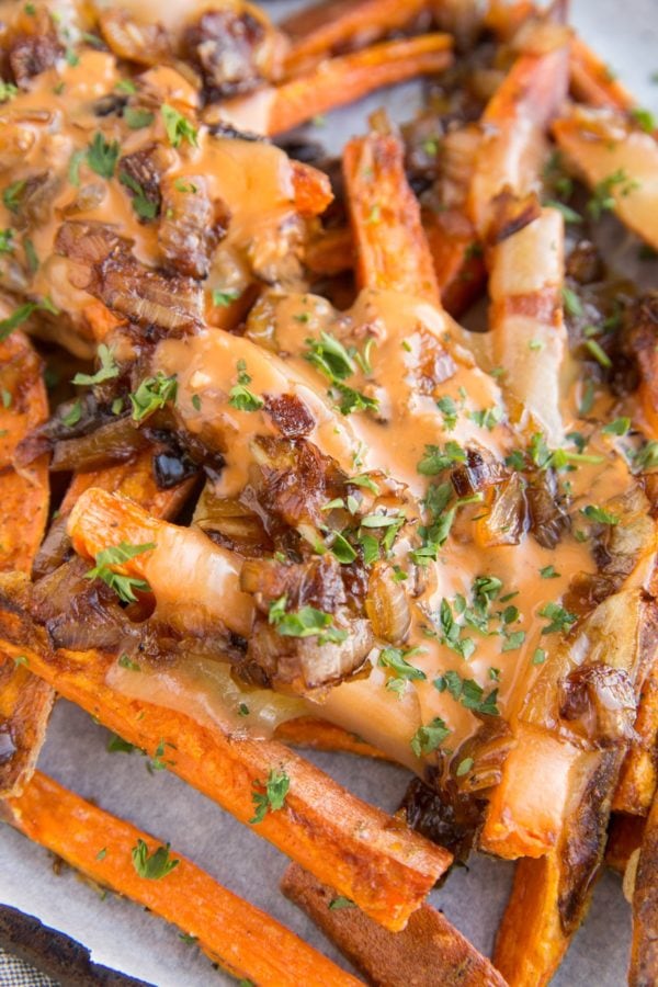 Sweet Potato Animal Style Fries - loaded fries with cheese, caramelized onions and special sauce on a parchment-lined baking sheet.