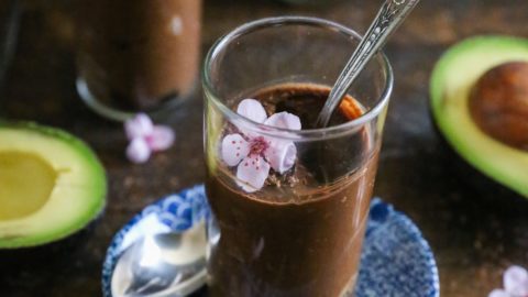Three dessert glasses with chocolate mousse inside with chocolate shavings all around.