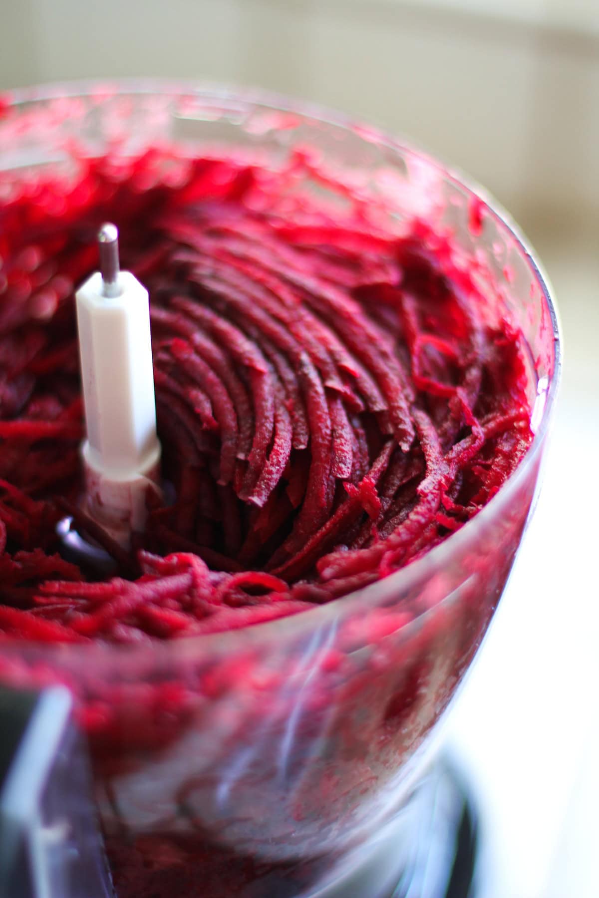 Shredded beets in the bowl of a food processor. Having used the grating attachment to make beet shreds.
