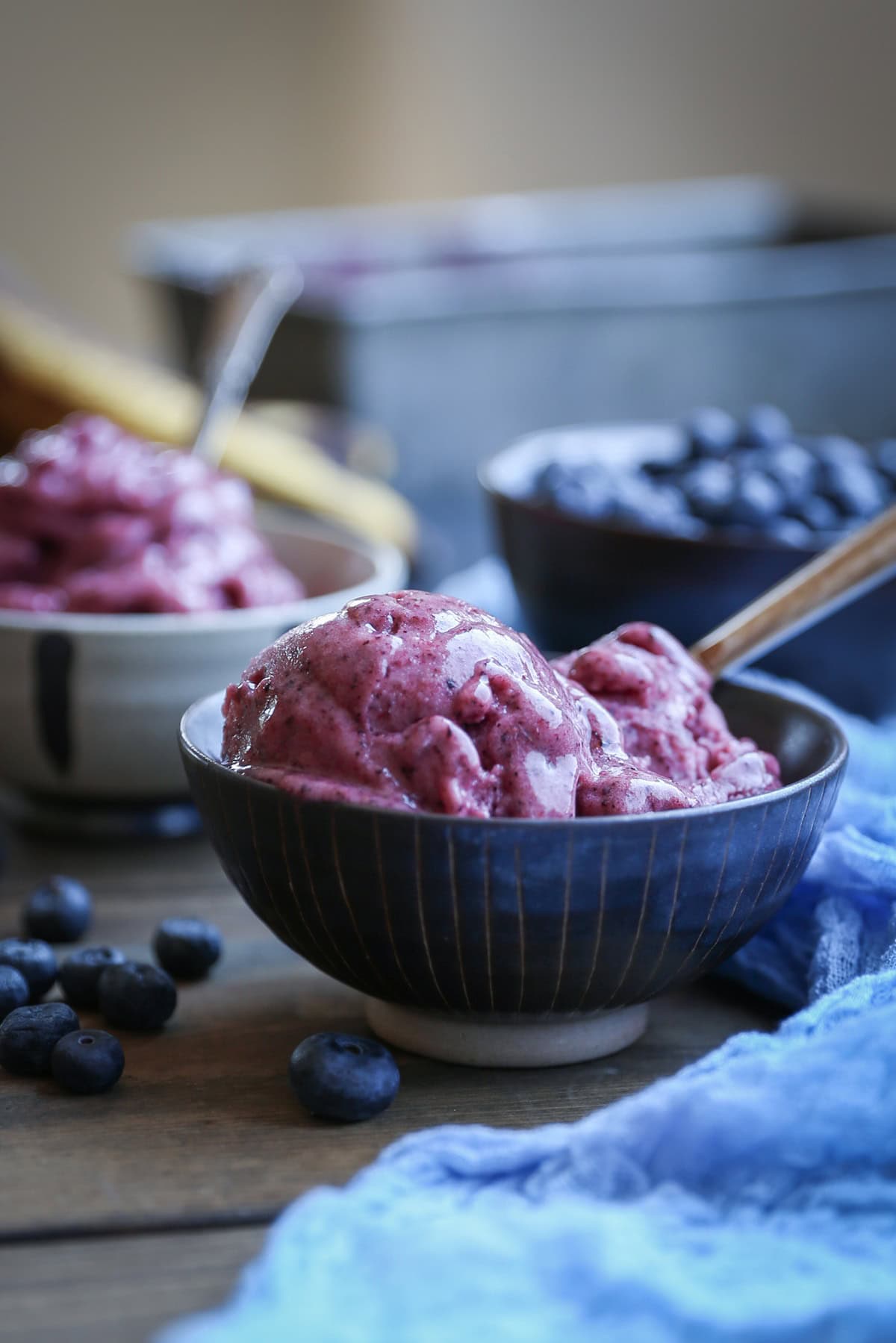 Two bowls full of berry ice cream with a blue napkin and spoons ready to eat.