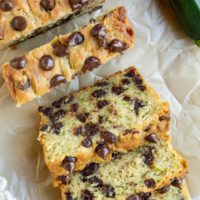 Loaf of zucchini bread on a sheet of parchment paper cut into slices.