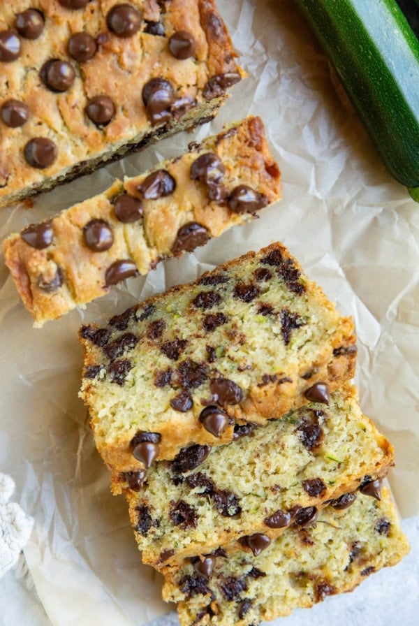 Loaf of zucchini bread on a sheet of parchment paper cut into slices.