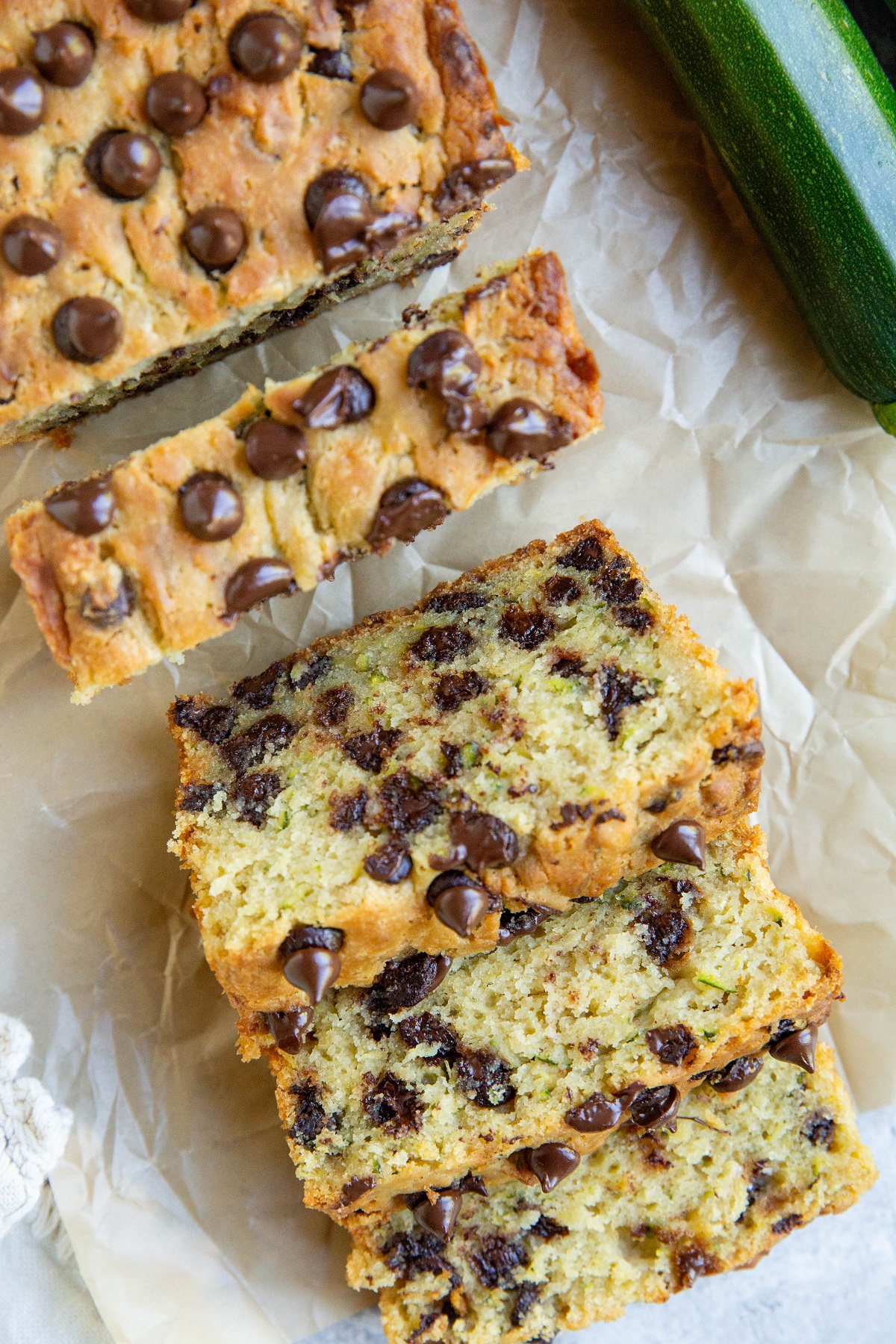 Loaf of zucchini bread on a sheet of parchment paper cut into slices.