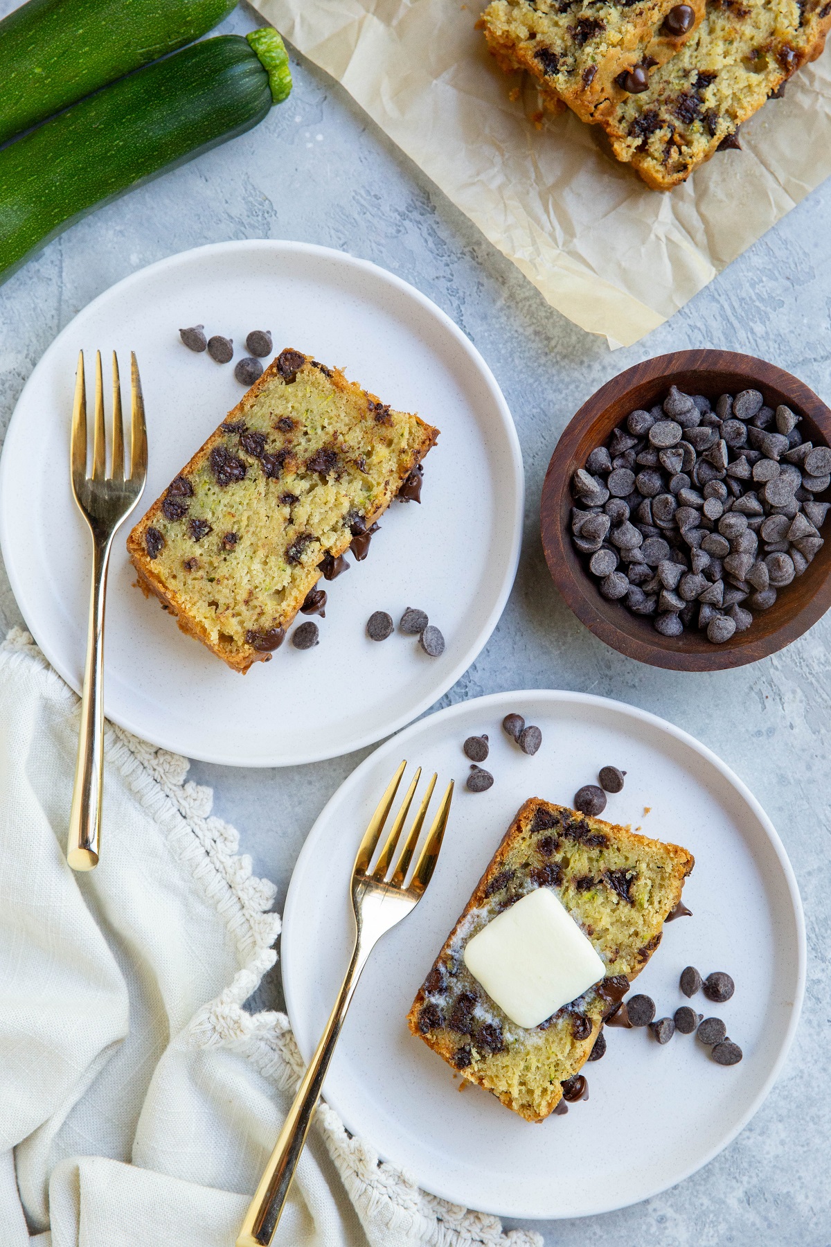 Two slices ofluten Free Zucchini Bread on two white plates with gold forks