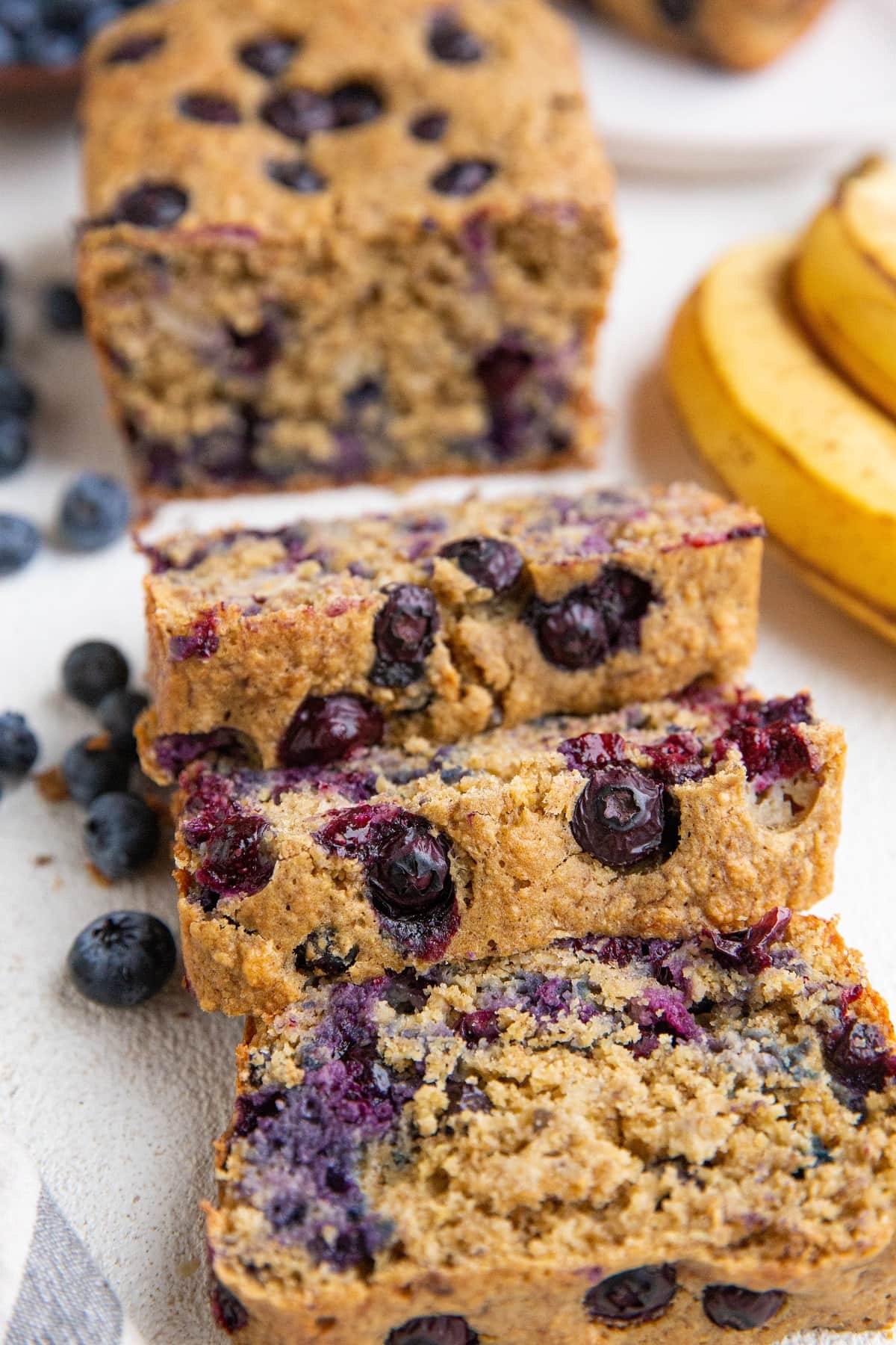 Thick slices of blueberry banana bread on a white background.