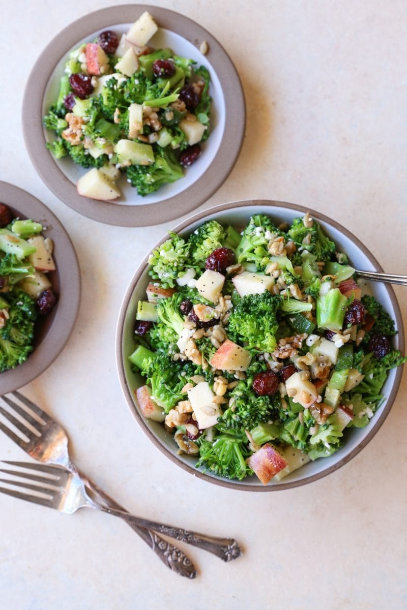 One large bowl full of broccoli salad and two little plates with broccoli salad. Ready to serve.