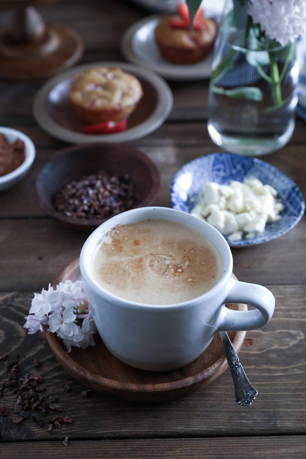 Mug of bulletproof coffee on a wooden table with muffins in the background.