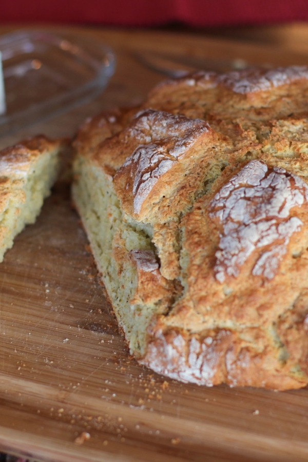 Loaf of bread on a cutting board with a slice cut out. Ready to eat.