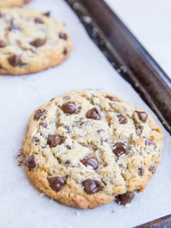 large low-carb chocolate chip cookies sitting on a baking sheet, ready to eat.