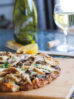 pizza with pesto sauce on a cutting board, sliced into slices.