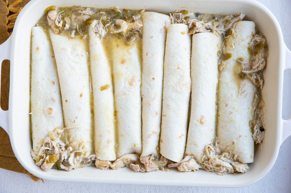 Chicken enchiladas in a baking dish, ready for the sauce to be poured on.