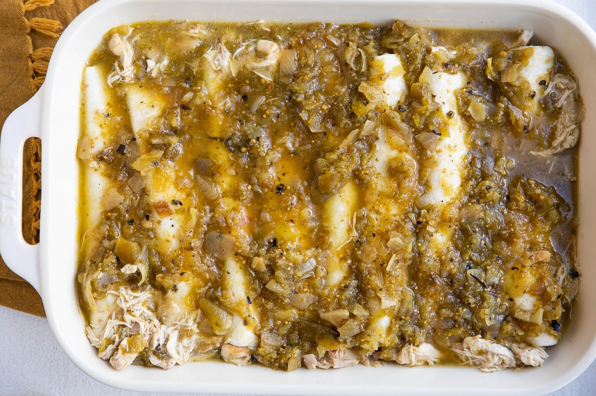Enchiladas covered with salsa verde, ready to be sprinkled with cheese.