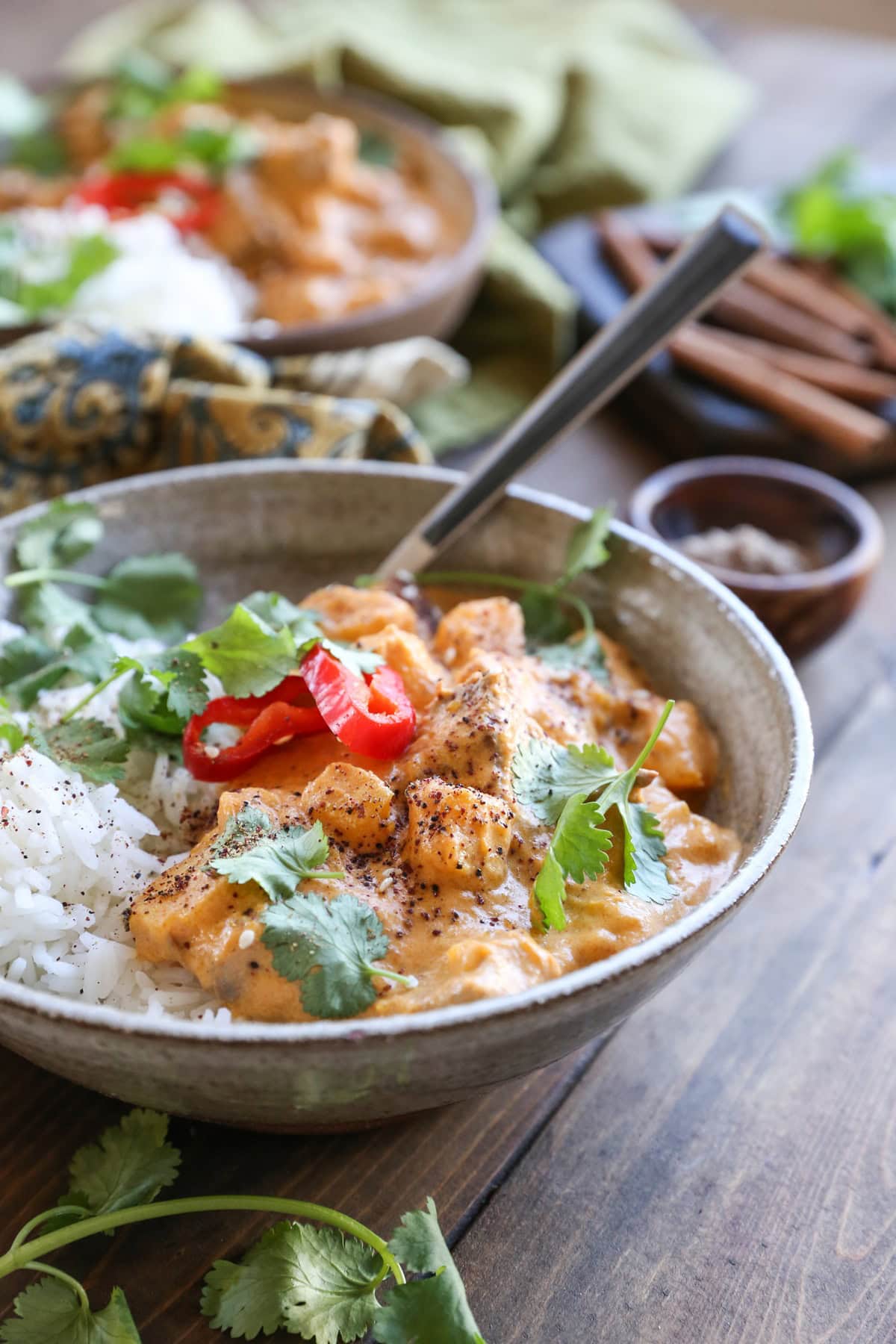 Chicken massaman curry in a ceramic bowl with fresh cilantro all around.