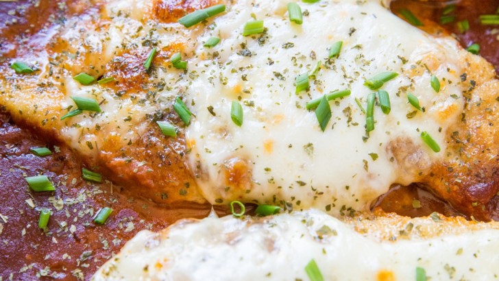 Cheesy baked chicken parmesan with mozzarella cheese and tomato sauce in a baking dish, fresh out of the oven.