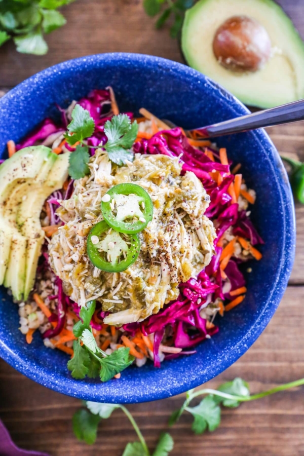 Blue bowl with rice, chile verde chicken, cabbage slaw, and avocado.
