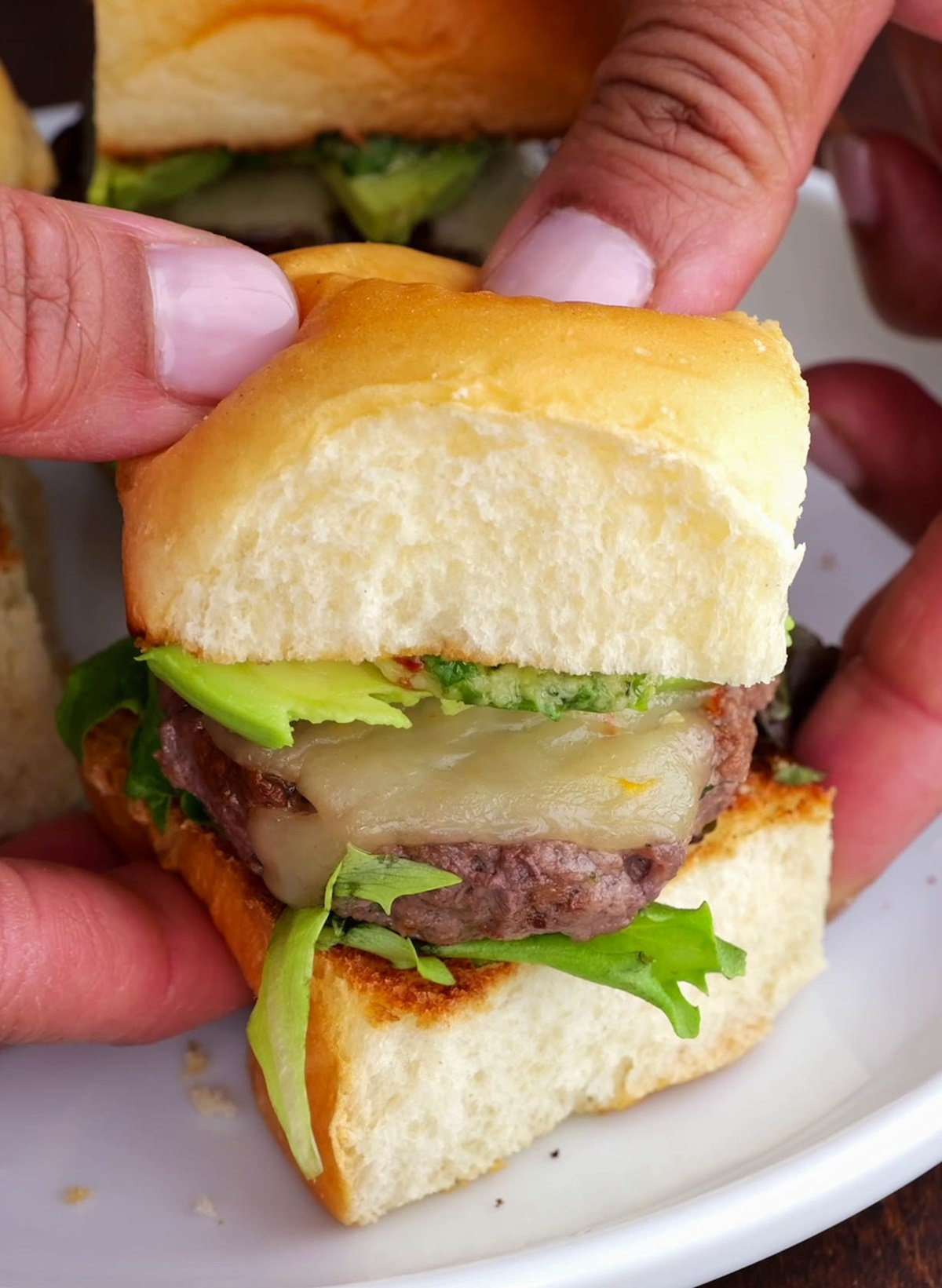 Hand picking up a beef slider to eat it.