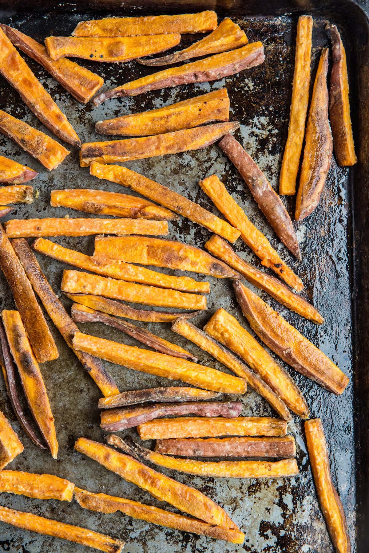 Baking sheet with crispy baked sweet potato fries on top in a single layer, fresh out of the oven.