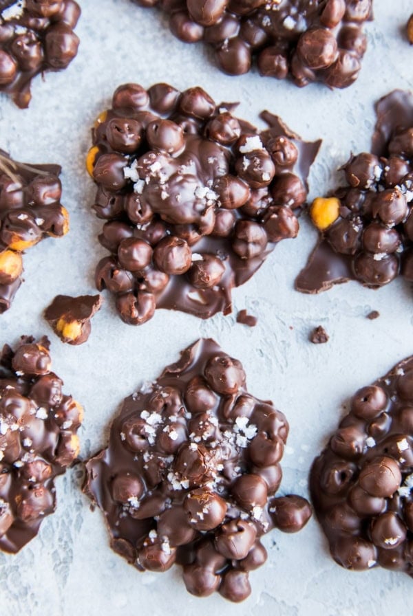 Chocolate Covered Chickpeas formed into lumps on a blue backdrop, sprinkled with sea salt.