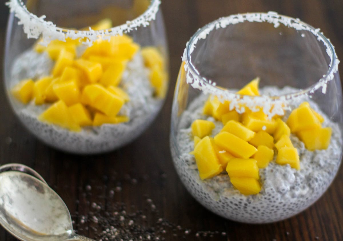 Two glasees of chia seed pudding with chopped mangos on top, ready to eat.