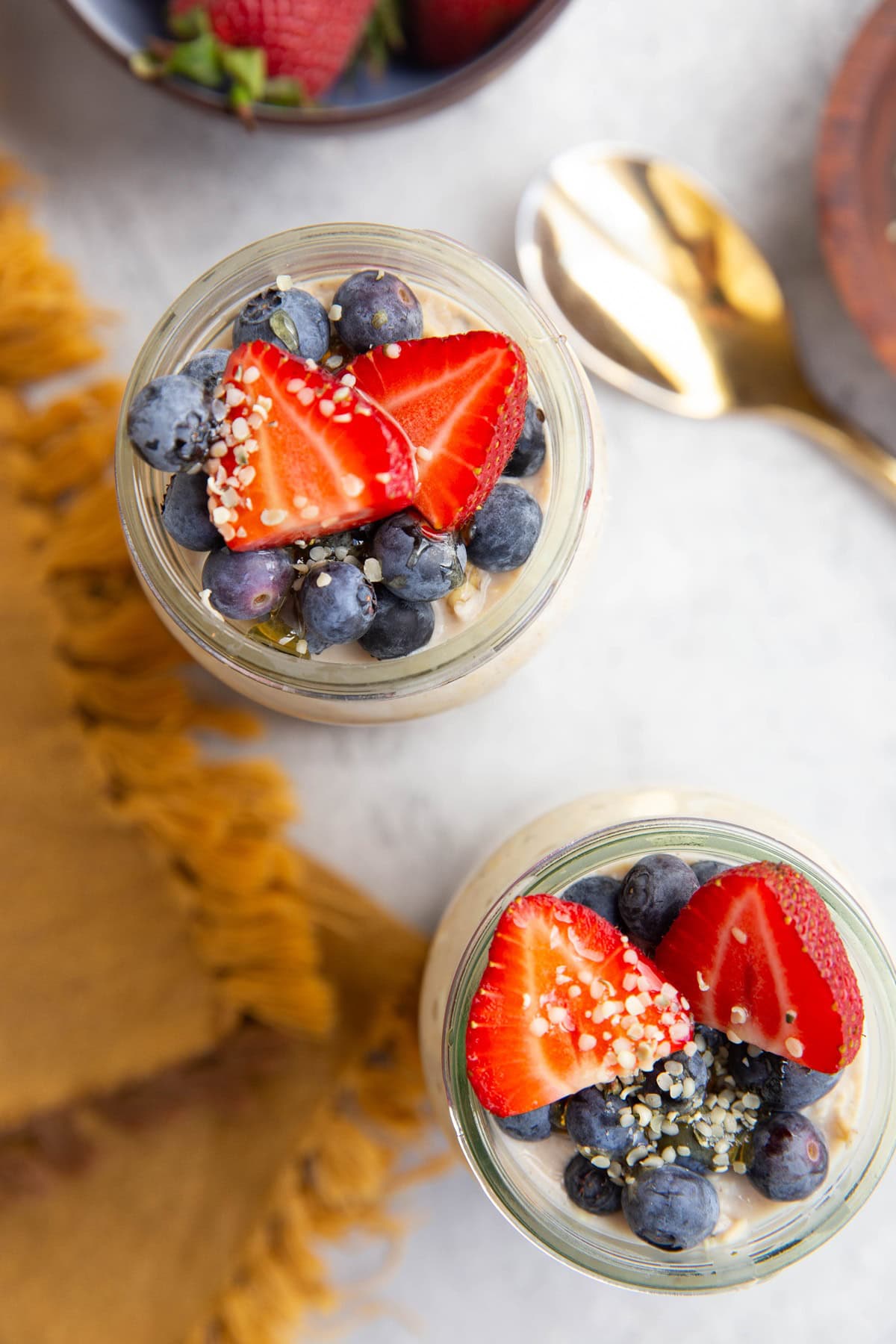 Two glasses filled with cottage cheese overnight oats with fresh fruit on top.