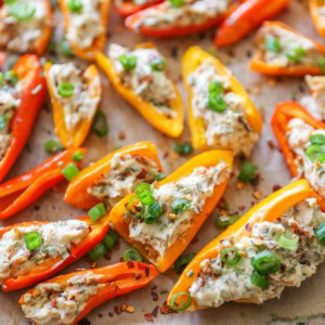 Baking sheet with cream cheese stuffed baby bell peppers on top.