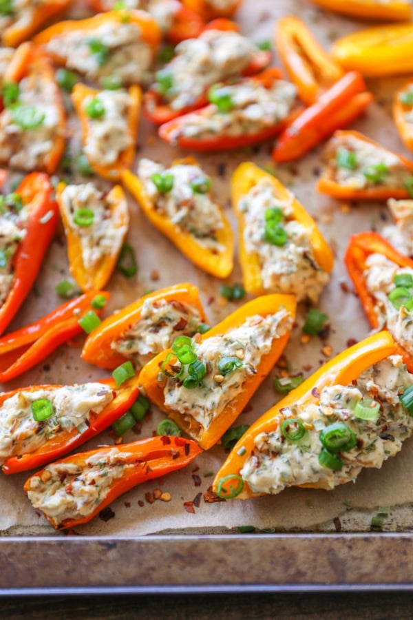Baking sheet with cream cheese stuffed baby bell peppers on top.