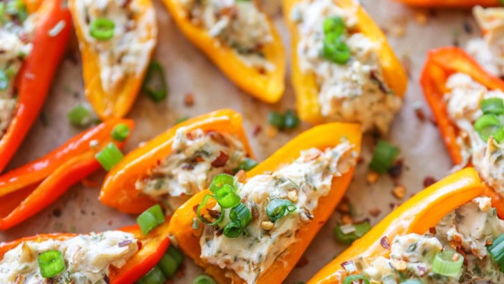 Baking sheet with cream cheese stuffed baby bell peppers on top.