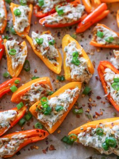 Rimmed baking sheet of mini sweet peppers stuffed with cream cheese.
