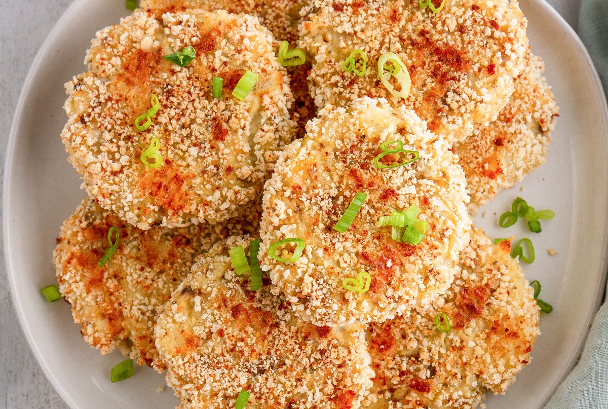 Plate of cauliflower potato cakes with green onions sprinkled on top, ready to be served.