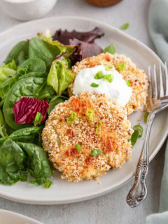 Cauliflower potato cakes on a white plate with a side salad, ready to serve.