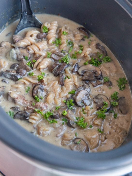 Crock pot full of creamy beef stroganoff, ready to serve.