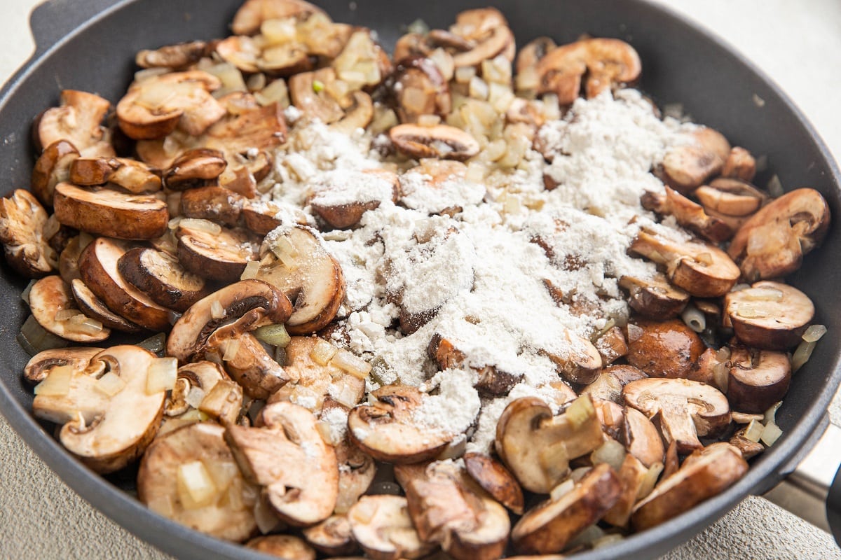 Flour in a skillet with onions and mushrooms.
