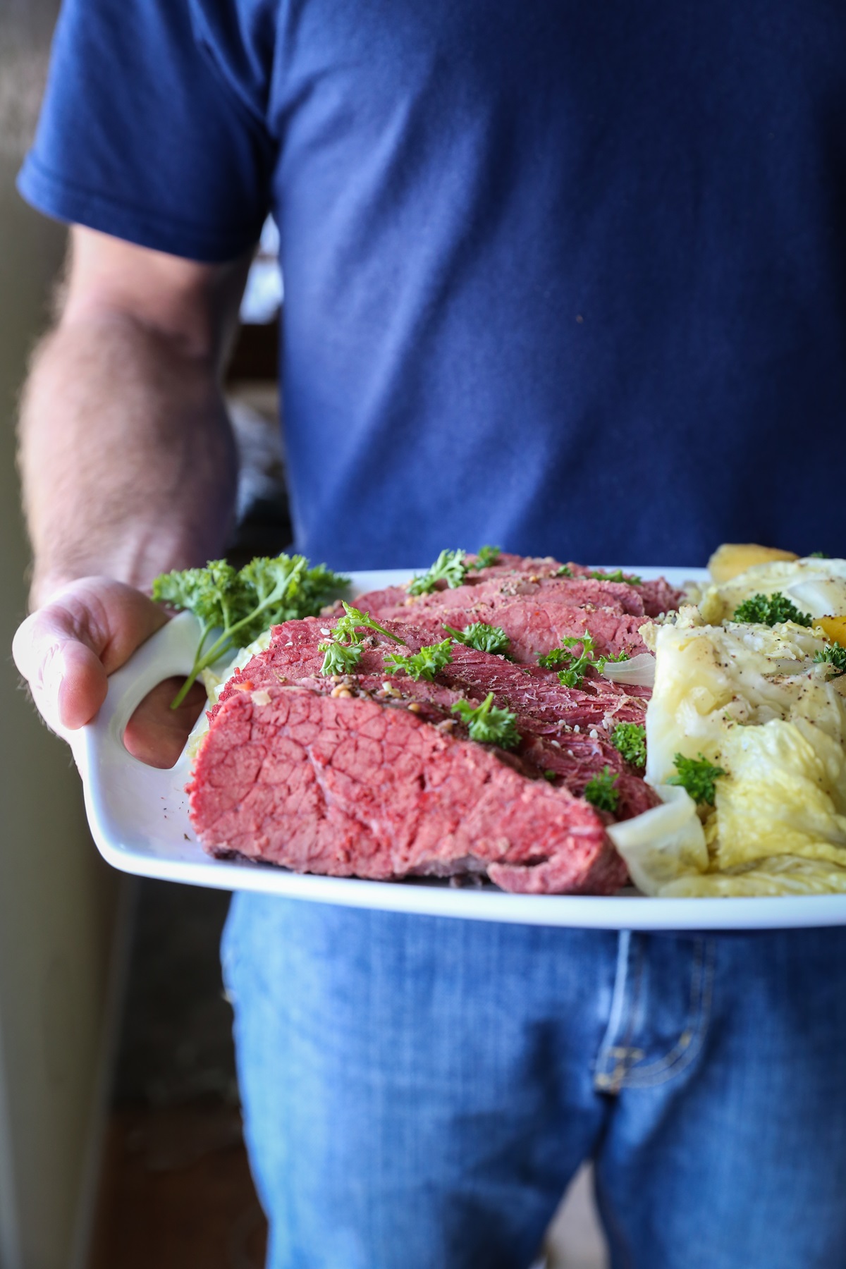 Man holding a plate of corned beef and cabbage, ready to serve.