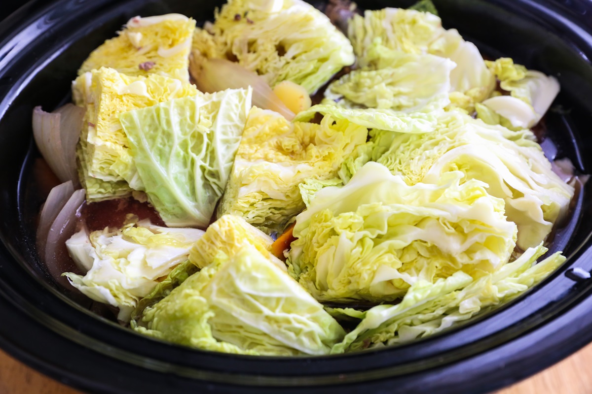 Crock Pot full of corned beef with cabbage chunks added on top.