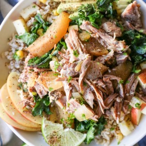 Bowl full of pulled pork, brown rice, avocado, sauteed kale and seasonings.