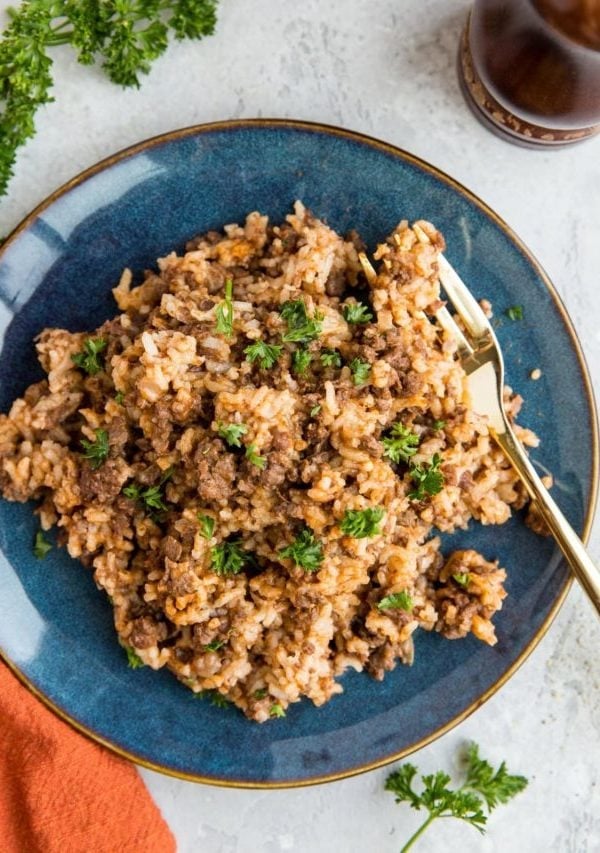 Blue plate of hamburger helper with rice, sprinkled with parsley.
