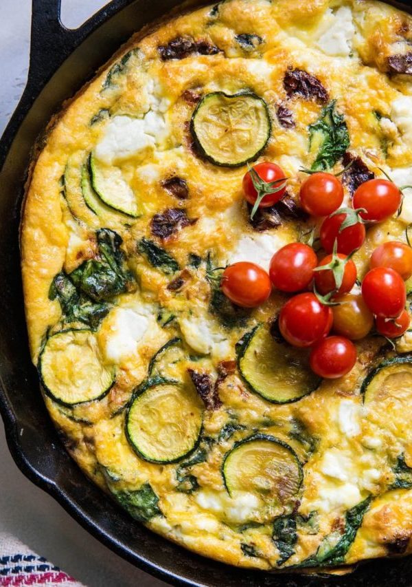 Spinach Frittata with Zucchini, Sun-Dried Tomatoes, and Goat Cheese in a cast iron skillet.