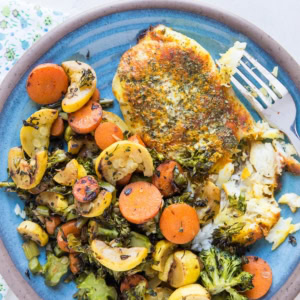 Easy Baked Cod Recipe with turmeric and paprika on a blue plate with roasted vegetables.